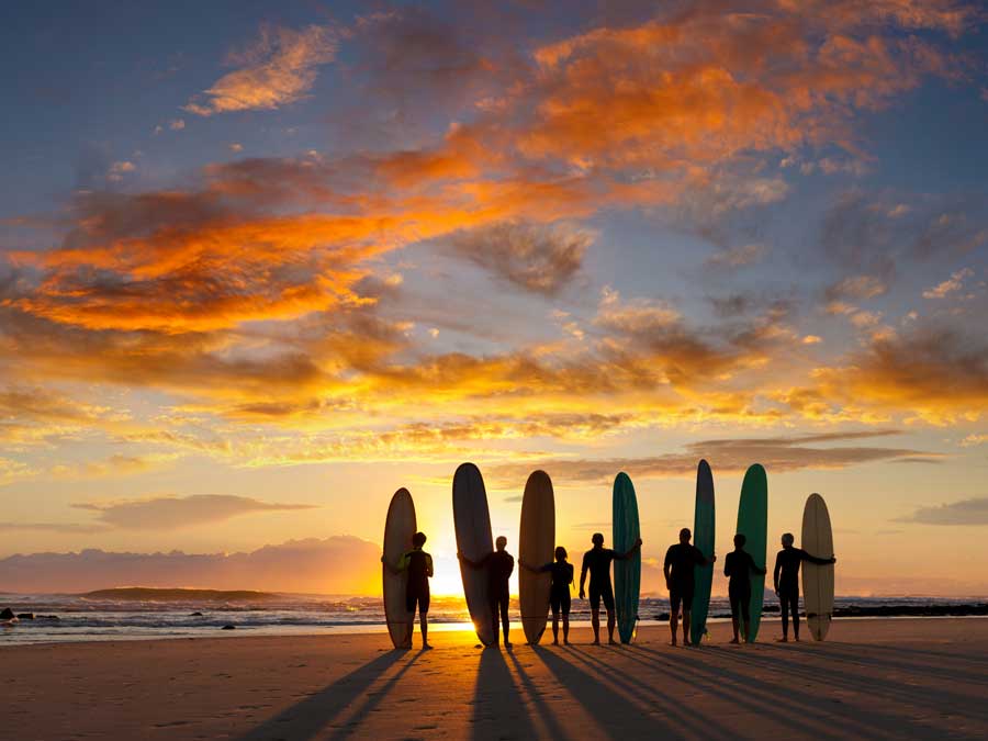 Surfers on the beach at sunset